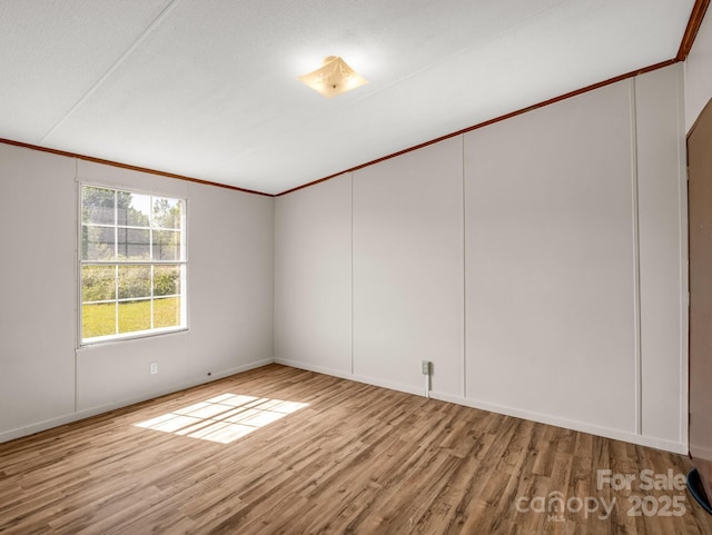 unfurnished room with baseboards, ornamental molding, and wood finished floors