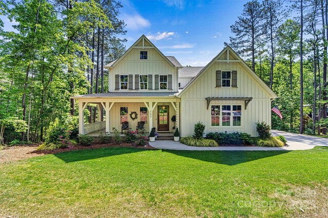 view of front of home with board and batten siding, covered porch, and a front yard