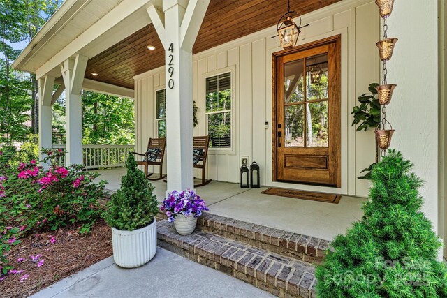 property entrance with covered porch and board and batten siding