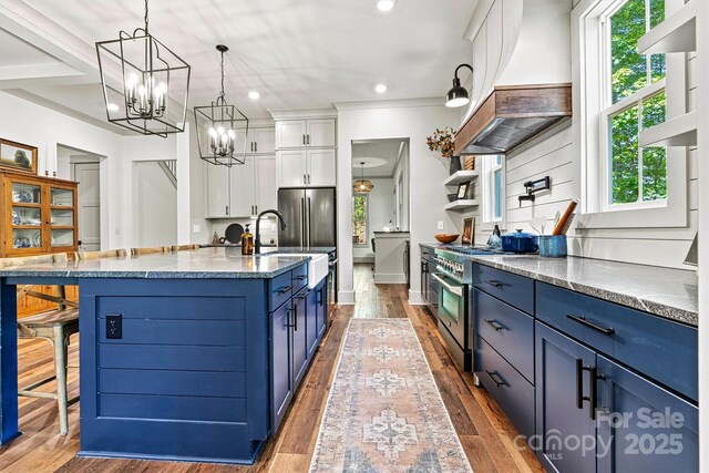 kitchen featuring appliances with stainless steel finishes, white cabinetry, wood finished floors, custom exhaust hood, and blue cabinets