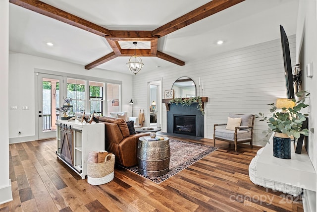 living area featuring a notable chandelier, beam ceiling, a glass covered fireplace, hardwood / wood-style floors, and recessed lighting