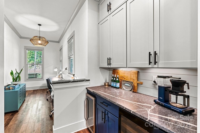 bar with dark wood-style flooring, hanging light fixtures, a dry bar, baseboards, and wine cooler