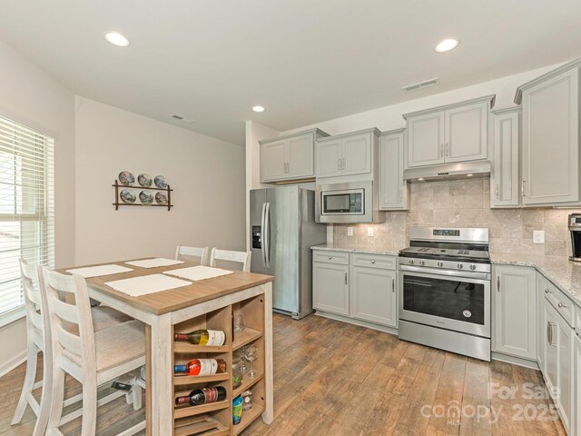 1026 Kirby Dr, Fort Mill, SC 29715 - kitchen featuring stainless steel appliances, under cabinet range hood, wood finished floors, backsplash, and recessed lighting
