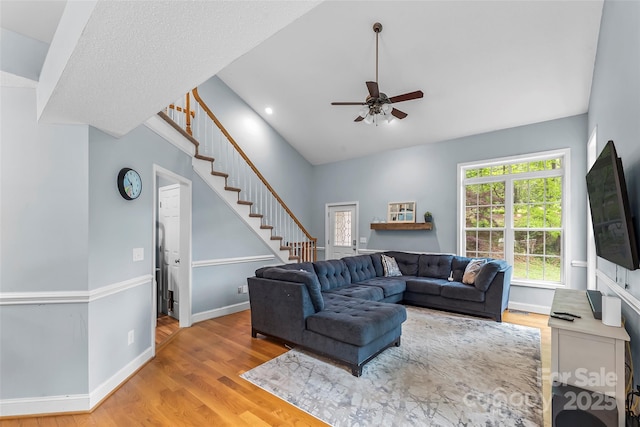 living room featuring a ceiling fan, baseboards, wood finished floors, and stairway