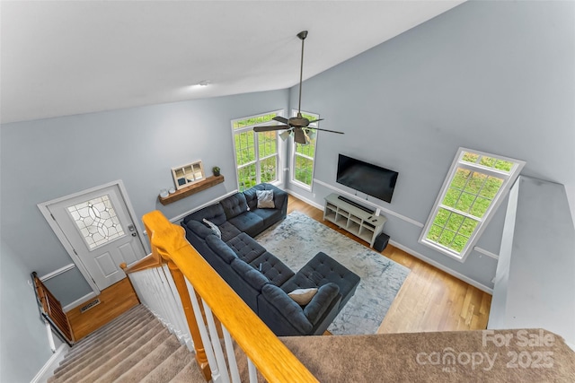 living area featuring baseboards, ceiling fan, wood finished floors, and vaulted ceiling
