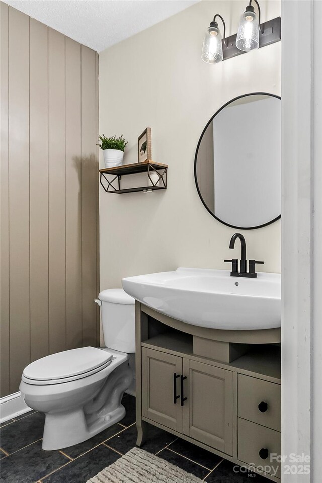 half bathroom featuring vanity, tile patterned floors, and toilet
