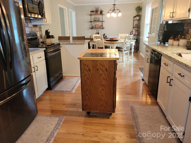 854 Silver Fox Dr, Concord, NC 28025 - kitchen featuring black appliances, ornamental molding, light wood-style floors, white cabinetry, and decorative backsplash