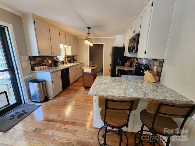 854 Silver Fox Dr, Concord, NC 28025 - kitchen with black appliances, a peninsula, light wood-style floors, tasteful backsplash, and ornamental molding