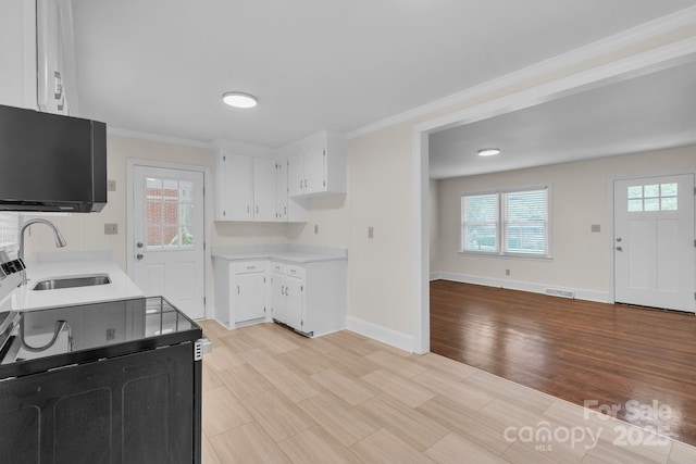 kitchen with baseboards, white cabinets, light countertops, and a sink