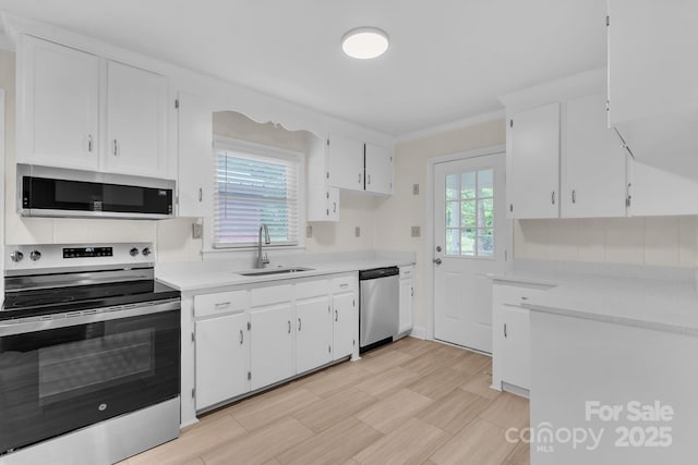 kitchen with stainless steel appliances, light countertops, white cabinets, and a sink