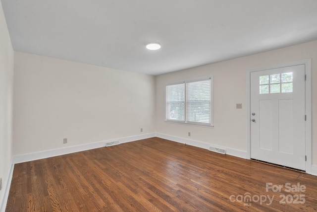foyer entrance with visible vents, baseboards, and dark wood-type flooring