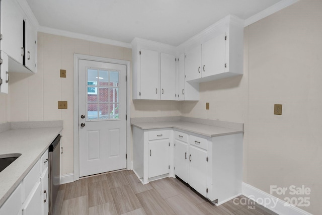 kitchen featuring light countertops, stainless steel dishwasher, baseboards, ornamental molding, and white cabinets