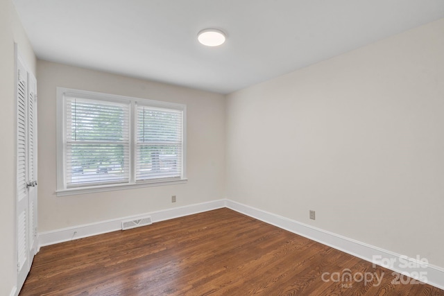 spare room with baseboards, visible vents, and dark wood-type flooring
