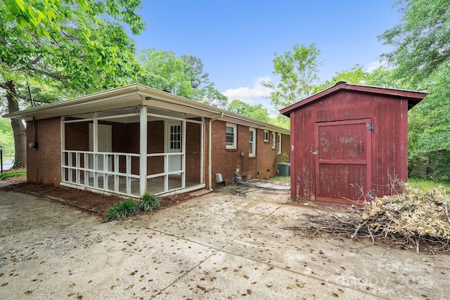 rear view of property featuring a shed, brick siding, and an outbuilding
