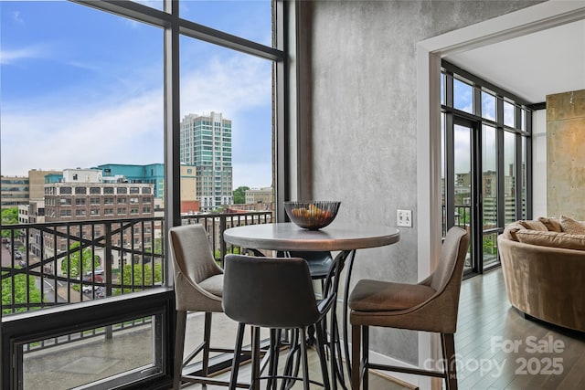 dining space featuring floor to ceiling windows, a healthy amount of sunlight, and a city view