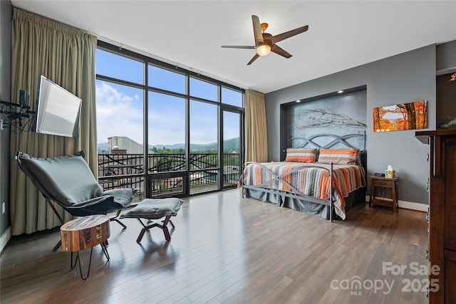 bedroom featuring access to outside, baseboards, floor to ceiling windows, and wood finished floors