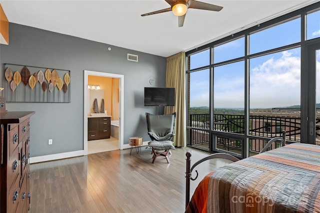 bedroom with visible vents, wood finished floors, expansive windows, baseboards, and access to outside