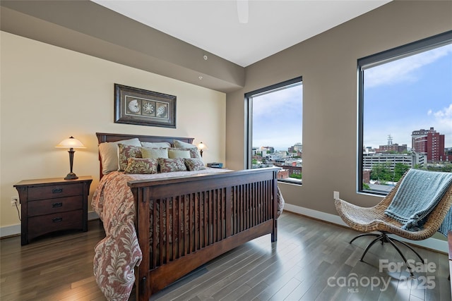 bedroom featuring baseboards, a city view, a ceiling fan, and wood finished floors
