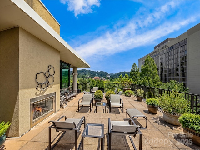 view of patio with a glass covered fireplace and fence