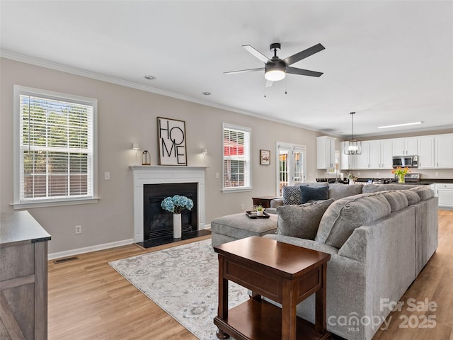 3 Holmes Ln, Arden, NC 28704 - living room featuring a fireplace with flush hearth, crown molding, light wood finished floors, and ceiling fan with notable chandelier