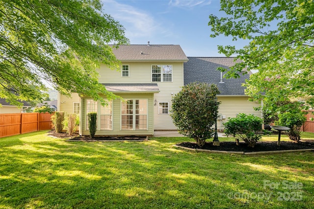 back of house with fence, a shingled roof, and a lawn