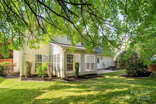 back of house featuring a shingled roof, a yard, fence, and central AC