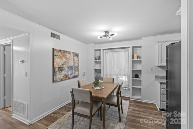 dining room featuring visible vents, baseboards, crown molding, and dark wood-style floors