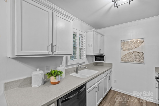 kitchen with ornamental molding, wood finished floors, light countertops, a sink, and dishwasher