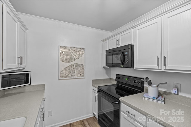 kitchen with light countertops, white cabinets, black appliances, and crown molding