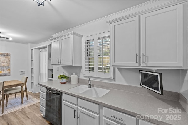 kitchen with white cabinets, a sink, light countertops, light wood-type flooring, and dishwashing machine