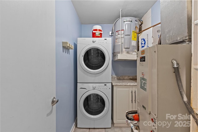 washroom with cabinet space, water heater, light tile patterned floors, and stacked washer / dryer