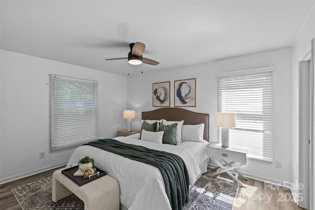 bedroom with baseboards, multiple windows, and wood finished floors