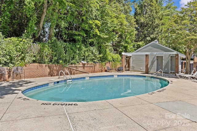 pool featuring a patio, an outdoor structure, and fence