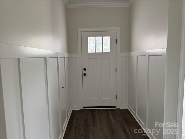 entryway featuring dark wood finished floors, crown molding, and a decorative wall