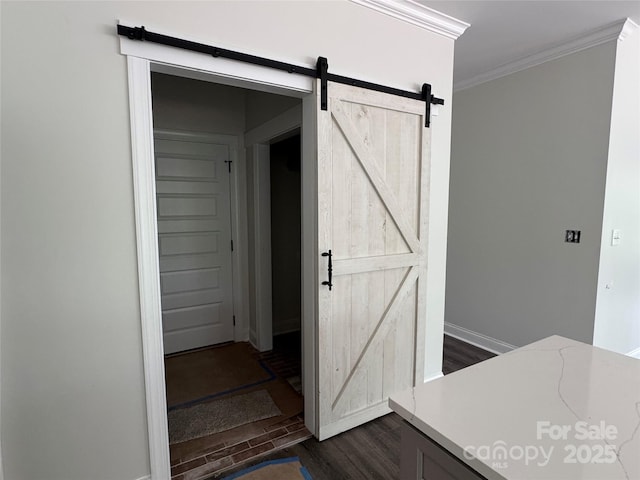 corridor featuring ornamental molding, dark wood-style floors, a barn door, and baseboards