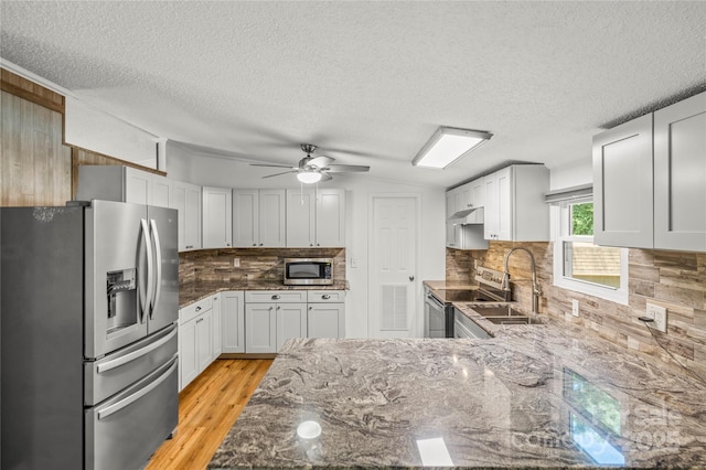 1005 Caldon Dr, Stanley, NC 28164 - kitchen featuring stainless steel appliances, a textured ceiling, dark stone counters, tasteful backsplash, and light wood-style floors