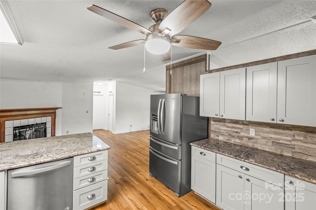 1005 Caldon Dr, Stanley, NC 28164 - kitchen featuring stainless steel appliances, a ceiling fan, a textured ceiling, light wood-type flooring, and a tile fireplace