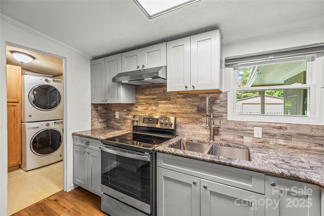 1005 Caldon Dr, Stanley, NC 28164 - kitchen featuring under cabinet range hood, appliances with stainless steel finishes, stacked washer / drying machine, a textured ceiling, and backsplash