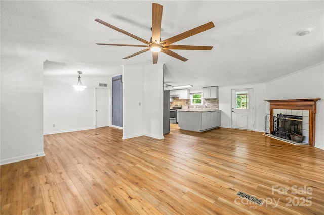 1005 Caldon Dr, Stanley, NC 28164 - unfurnished living room featuring a ceiling fan, a tile fireplace, and light wood finished floors