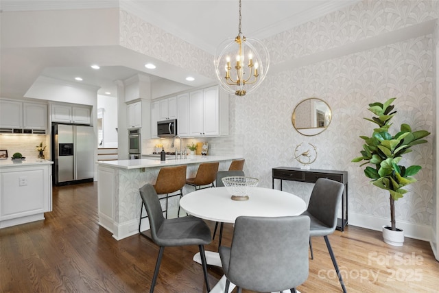 dining area with crown molding, wood finished floors, wallpapered walls, a chandelier, and recessed lighting