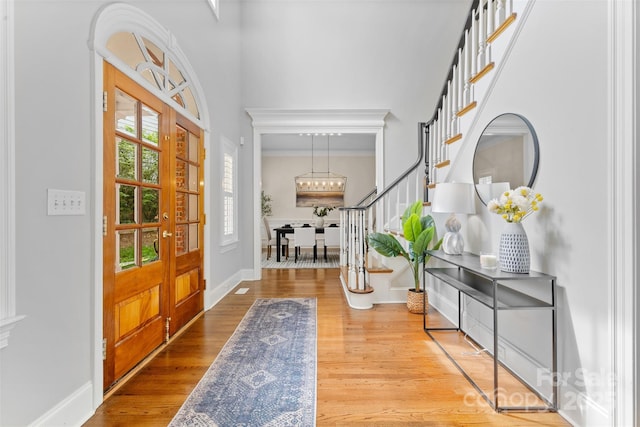 foyer with stairway, baseboards, crown molding, and wood finished floors