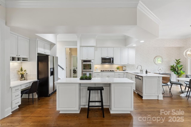 kitchen featuring a kitchen breakfast bar, a sink, a peninsula, washer / dryer, and stainless steel appliances