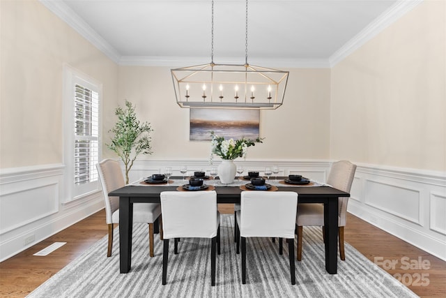 dining area featuring a chandelier, ornamental molding, and wood finished floors