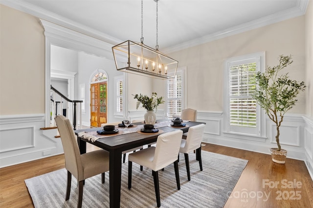 dining area featuring an inviting chandelier, wainscoting, and wood finished floors