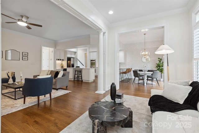 living area featuring crown molding, dark wood-style flooring, ceiling fan, and ornate columns