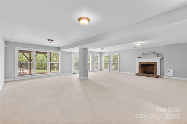 unfurnished living room featuring a brick fireplace, baseboards, and carpet flooring
