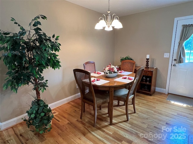 dining area featuring baseboards, light wood-style floors, and a notable chandelier