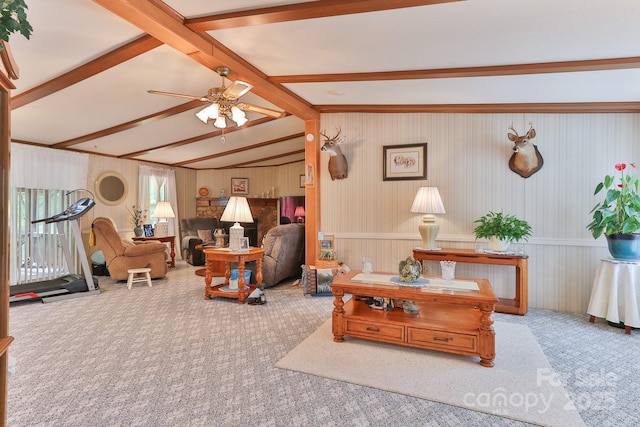 living area featuring carpet flooring, ceiling fan, vaulted ceiling with beams, and wainscoting