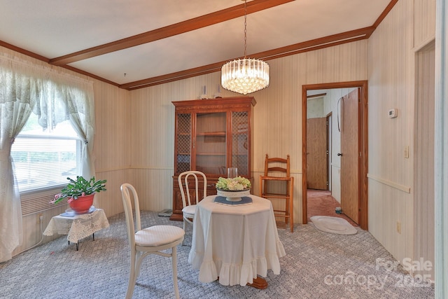 dining area featuring carpet flooring, beam ceiling, a notable chandelier, wood walls, and ornamental molding