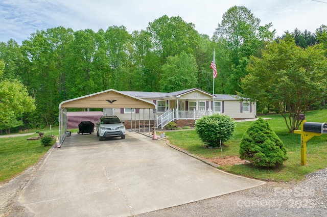 manufactured / mobile home with a porch, a carport, a front lawn, and driveway